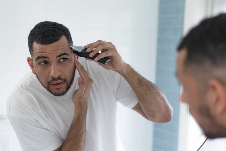 Mixed race male trimming and grooming in his bathroom