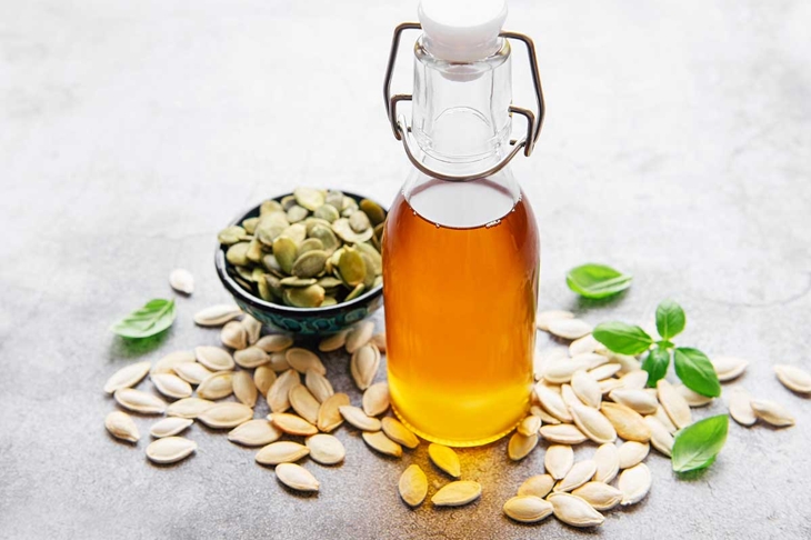 Bottle with pumpkin seed oil on gray concrete background